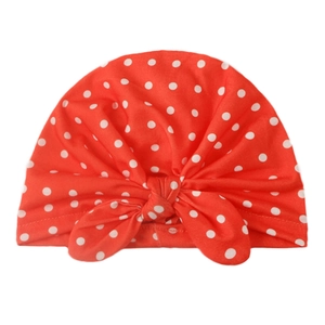 Détail du bonnet turban rouge pour bébé à pois blancs avec un grand nœud papillon