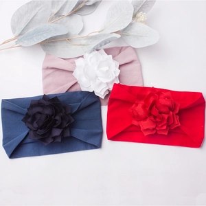 Detailed view of three soft fabric baby headbands with 3D floral accents in red, navy, and pink