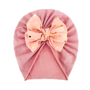 Dettaglio del turbante per neonati con grande fiocco rosa e pois dorati metallizzati