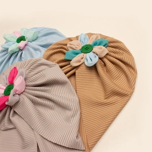 Dettaglio di turbanti per neonati con texture a maglia, fiori di stoffa e bottoni decorativi