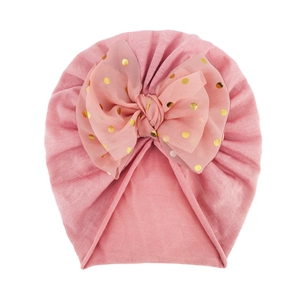 Dettaglio del turbante neonata con fiocco in rete rosa a pois dorati e tessuto di cotone