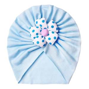 Sky blue infant turban hat with a polka dot floral detail on a white background