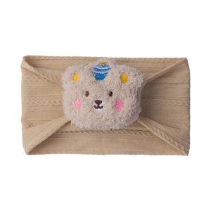 Detailed macro view of beige cable-knit baby headband with cute plush bear ornament