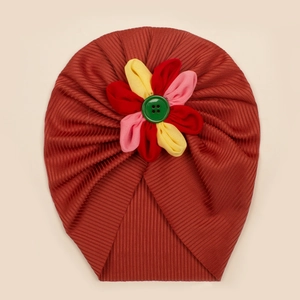 Dettaglio del turbante per neonati con fiore colorato e bottone verde su tessuto a coste