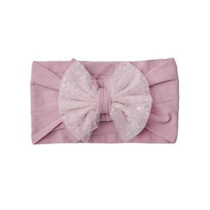 Detail view of pink baby headband with large sequin mesh bow on soft nylon fabric