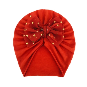 Dettaglio cappello a turbante rosso per neonati con fiocco in tulle a pois oro