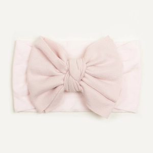 Close-up of soft baby pink nylon headband featuring a large decorative bow for infants