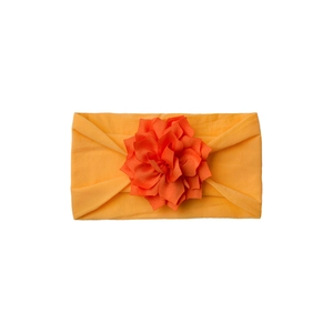 Detail of soft elastic headband featuring a large layered yellow fabric flower for infants