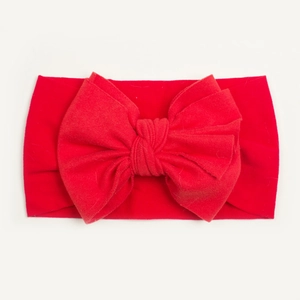Detail of red nylon baby headband featuring a large bow and soft ribbed texture