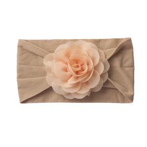 Close-up of baby headband featuring a soft beige elastic band and large layered chiffon flower