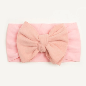 Detail of soft pink baby nylon headband featuring a large hand-tied bow decoration