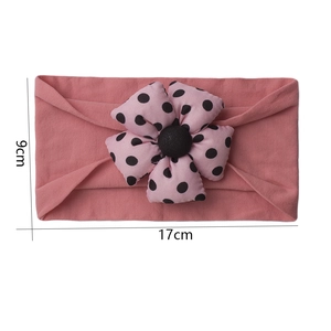 Detail view of pink baby headband with polka dot flower measuring 17cm by 9cm