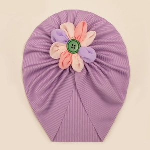 Dettaglio del turbante per neonati con fiore di stoffa multicolore e bottone verde centrale