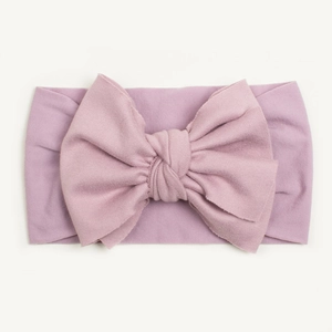 Close-up of soft pale purple baby headband with large bow and elastic knit texture