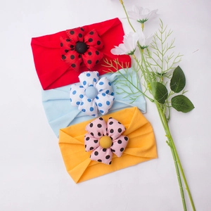 Three-piece set of elastic baby headbands with large polka dot flowers in red, blue, and yellow