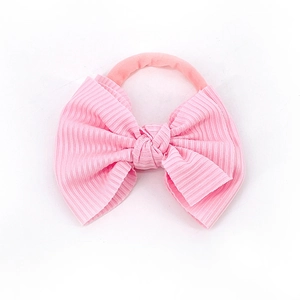 Détail d'un bandeau bébé en maille côtelée avec un grand nœud rose pâle fait à la main