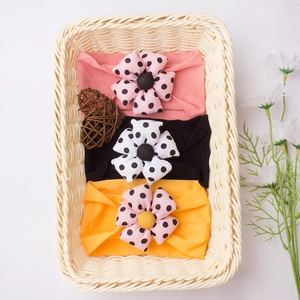 Detailed close-up of three baby headbands with large polka dot flowers in a woven basket