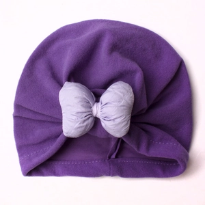 Detail of baby turban hat in purple velvet with oversized pleated bow decoration