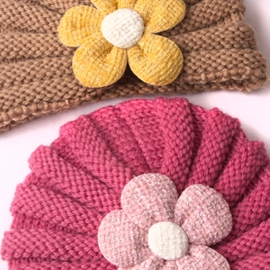 Detail of baby knitted headbands with 3D tweed flowers in brown and rose red colors