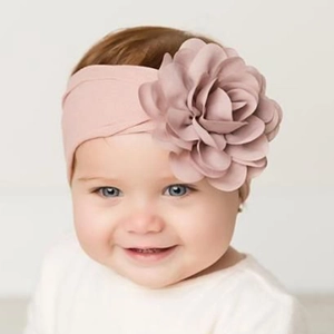 Vue détaillée d'un bandeau en nylon rose poudré doux avec une grande fleur 3D pour bébés