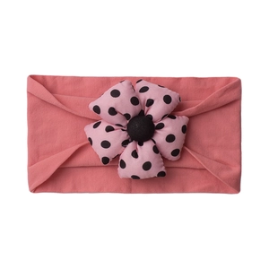 Detail of pink baby headband with large black polka dot fabric flower decoration