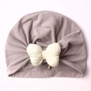 Close-up of baby knot hat with plush warm fabric and a cream-colored soft bow detail