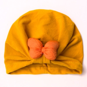 Detailed view of ginger yellow baby beanie featuring a vibrant orange fabric bow tie knot