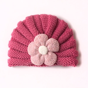 Close-up of soft ribbed knit baby hat with decorative fabric flower detail in rose pink