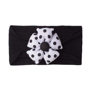 Detail of baby elastic headband featuring soft black fabric and polka dot floral ornament