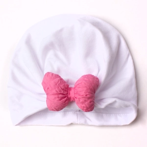 Detail of soft white baby turban hat featuring a bright pink textured bow on plain background
