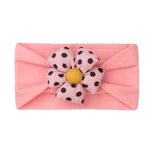 Close-up of pink elastic baby headband with large polka dot flower and yellow center