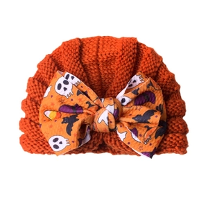 Orange knitted Halloween baby turban hat with oversized festive bow and skull pattern