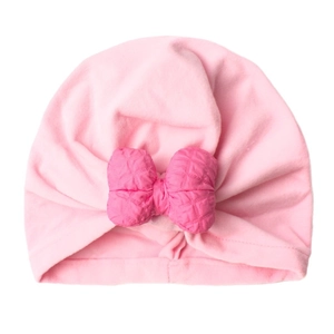 Pink newborn turban hat with quilted bow detail for warmth and style on white background