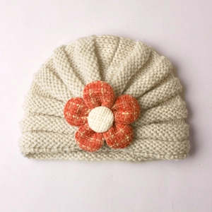 Detailed texture of baby knitted beanie with orange tweed flower decoration