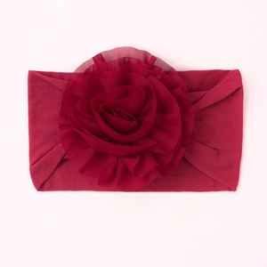 Détail d'un bandeau souple pour bébé bordeaux avec une fleur en mousseline multicouche