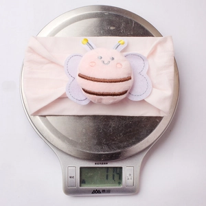Macro shot of a lightweight pink baby headband with a plush bee weighing only 11.4 grams