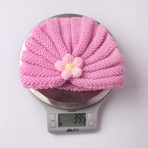 Detailed view of pink knitted baby hat weighing 39.5g on a digital scale for size check