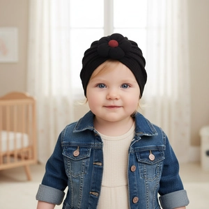 Detailed close-up of a black baby turban hat with a large 3D flower and rib-knit texture
