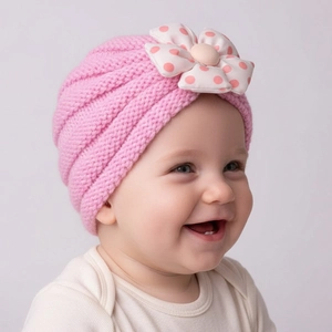 Detail of pink knitted baby turban hat with a large pink polka dot 3D floral decoration