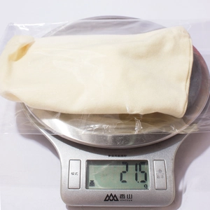 Detailed view of lightweight baby hat on kitchen scale showing 21.5g total weight