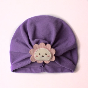 Detailed close-up of purple baby turban hat with cute cartoon lion patch and knit texture
