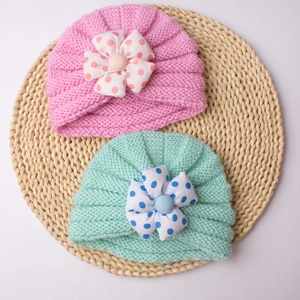 Knitted baby beanies with cute polka dot fabric flowers in pink and mint green colors