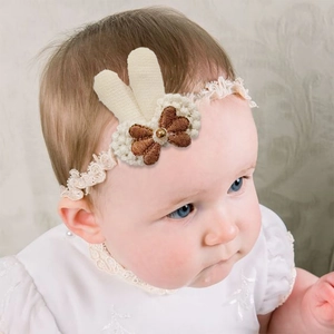 Detailed close-up of a baby headband featuring knit rabbit ears and lace trim on a model