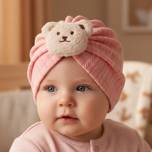 Nahaufnahme der weichen rosa Strick-Babymütze mit süßem Plüschbären-Aufnäher vorne