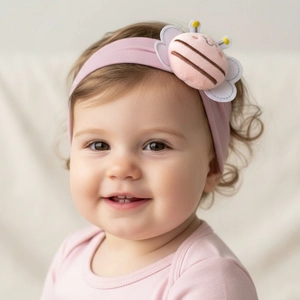Close-up of baby girl wearing a soft pink nylon headband with plush bee detail