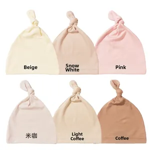 Detail showing soft cotton baby top knot hats in six neutral earthy tones