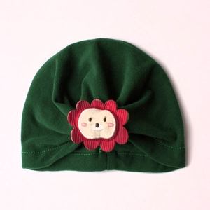 Close-up of baby turban hat in dark green fabric with cute lion patch detail