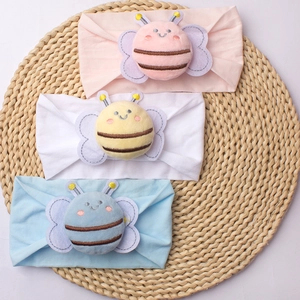 Detailed view of three soft nylon baby headbands with cute 3D plush bee decorations
