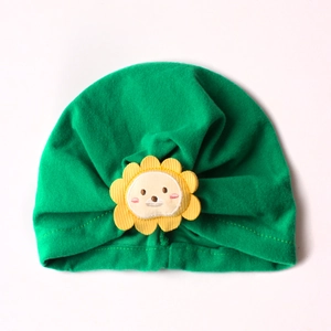 Close-up of green knit baby turban hat with cute yellow cartoon lion patch detail