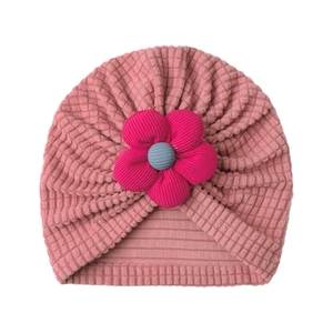 Detailed view of pink knitted baby hat featuring a large magenta floral decoration